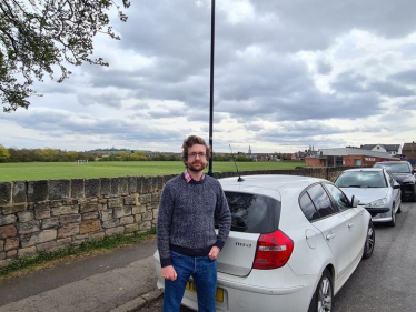 Alexander Stafford stands near parked vehicles on road