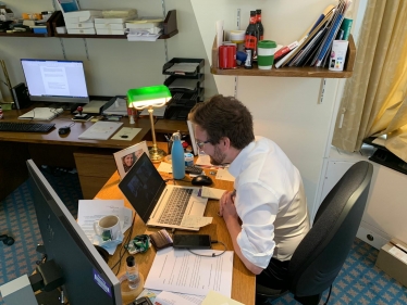 Alexander Stafford MP sits in front of his laptop to join school class on Zoom